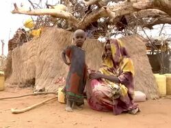 Woman and child by straw hut Stock Footage