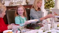 Mother and grandmother pass dishes and help fill young girl's plate at Christmas dinner Stock Footage