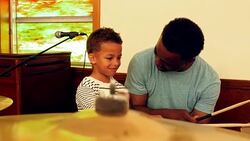 MS Smiling young boy during music lesson on drums with father Stock Footage