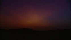 The sun illuminates a cloud over the desert as the sun sets. Stock Footage