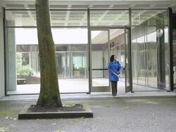 WS PAN Woman emerging from office building onto urban park walkway / Portland, Oregon, USA Stock Footage