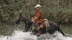 SLO MO DS Cowboys riding horses across river Stock Footage