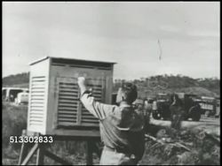 1942: US MILITARY WEATHER STATION: 'Weather Station' sign in unidentified location, man opening door of weather box (wet & dry bulbs, low/high temperature), same man climbing wind vane (direction, speed) looking at reading.  WWII, World War II. Instructional Video