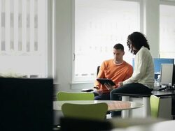 MS businessman and businesswoman sitting at workstation in office working on digital tablet  Stock Footage