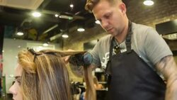 Male Hair stylist drying a female clients hair Stock Footage