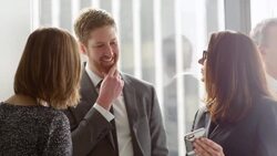 MS Mature businesswoman presenting ideas on smartphone to colleagues during informal meeting in office Stock Footage