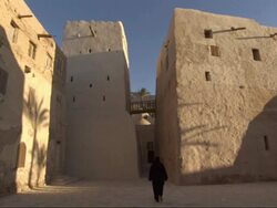 Wide Shot, static - A monk walks between the adobe buildings of a monastery / Egypt Stock Footage