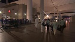 Travelers in traditional clothing carry luggage through a terminal in Saudi Arabia. Stock Footage