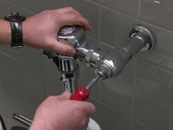 A hand uses a screwdriver on a water pipe for a toilet. Stock Footage