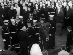 B/W 1963 soldiers + sailors passing folded flag from JFK's coffin to man + saluting / Arlington Stock Footage