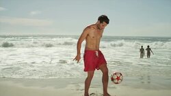 Young men playing with soccer ball on beach Stock Footage