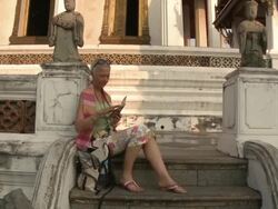 WS ZI MS Woman reading guidebook on temple steps, Wat Phra Kaew (Temple of the Emerald Buddha), Bangkok, Thailand Stock Footage