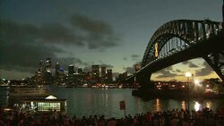 A cloudy sky glows at sunset behind Sydney Harbour Bridge near a New Year's Eve crowd. Stock Footage