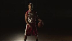 A basketball player dribbles a ball while standing at center court of a gym. Stock Footage