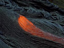 Wide shot red hot lava flowing over charred volcano surface / Hawaii Stock Footage