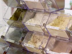 CU scooper spoon retrieves a scoop of hemp protein powder booster and PEA protein powder booster at juice bar as smoothie ingredients Stock Footage