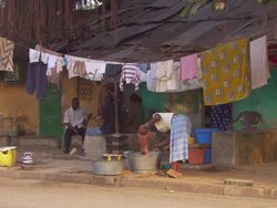WS Shot of baby being bathed by her mom in metal tub outside house / Conakry, Guinea Stock Footage
