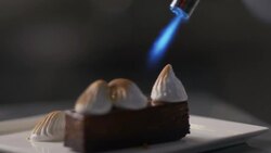 Pastry chef toasts marshmallow cream on s'mores dessert with kitchen blowtorch in restaurant. Stock Footage