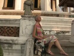 MS ZI CU Woman resting on temple steps, basking in sunlight, Wat Phra Kaew (Temple of the Emerald Buddha), Bangkok, Thailand Stock Footage