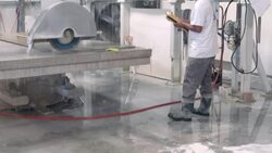 water dripping from table of computer controlled gantry saw as operator holds control in his hand and watches marble cutting process Stock Footage