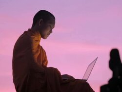 MS A Buddhist monk types on a laptop computer on top of an ancient temple at sunrise in Angkor Wat / Siem Reap, Cambodia Stock Footage