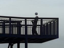 Low angle wide shot boy dribbling soccer ball on footbridge Stock Footage