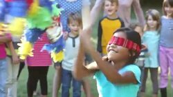 Girl hitting pinata, children watching in background Stock Footage