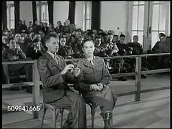 1945: MILITARY TRIBUNAL: EVIDENCE: LS U.S. Military Commission members sitting. MS Witness Joseph Pusch & interpreter handing airman's cap to prosecutor Victor Miles. CU Cap. MS Pusch & interpreter translating Pusch finding name on cap. Instructional Video