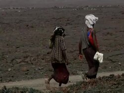 Two women walking through brown landscape Stock Footage