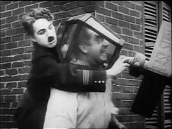B/W 1917 policeman Charlie Chaplin holding bent street lamp over head of large man + turning on gas Stock Footage