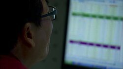 A man wearing glasses watches a table displayed on a computer screen. Stock Footage