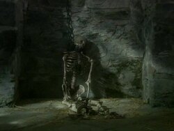 WS Seated skeleton wearing manacles and handcuffs and chained to dungeon walls by neck collar / Gwydir Castle, Wales, UK Stock Footage