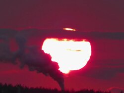 Extreme large sunset set against a polluting smokestack of an oil refinery Stock Footage