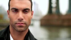 Man stares, smiles at camera in front of Manhattan Bridge on the East River Stock Footage