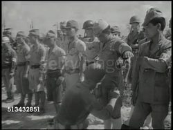 1945: OCCUPIED ROTA: VS Landing crafts approaching Rota island, United States soldier patting down surrendered Japanese soldiers, stack of rifles, Japanese soldiers marching w/ hands on head. World War II surrender, WWII, Pacific Front Instructional Video