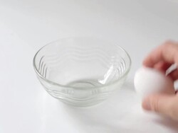 Hands cracking egg in a bowl on white background Stock Footage