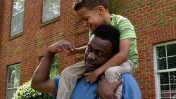 MS LA Smiling young boy riding on fathers shoulders on summer afternoon Stock Footage