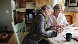 Senior women looking through photograph album at dining table Stock Footage