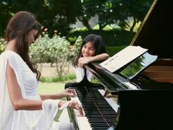 Young woman playing a piano with a girl watching her  Stock Footage