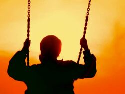 boy riding on a swing at sunset Stock Footage