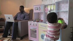 Father working on laptop and son playing with toy kitchen in living room Stock Footage