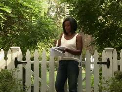 Black woman opening mail next to garden gate Stock Footage