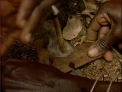 CU High angle, stick being used to make fire, tilt up to hands moving stick, Kenya Stock Footage