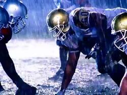 OVEREXPOSED football players at line of scrimmage, ball is snapped, players block each other / rain Stock Footage