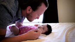 Father Playing with Infant Daughter on Bed Stock Footage