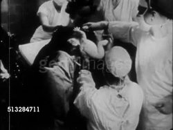 1960s: CHILDBIRTH: QUESTIONABLE QUALITY: VS Doctor delivering baby in hospital delivery room, showing crying baby to mother, nurses around, cleaning crying newborn infant. Labour, pregnancy, vaginal birth, children Instructional Video