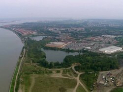 Aerial wide shot pan buildings, trees, and large car park in Woolwich on the Thames / London, England Stock Footage