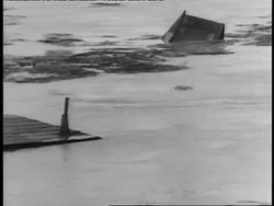 Townspeople watch buildings float under bridges in a destructive river flood. News Clip
