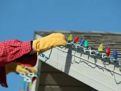 Man Removing LED Christmas Lights from a House Roof Stock Footage