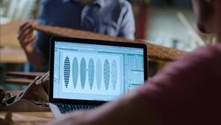 Wood shop worker on laptop computer studies intricate skateboard designs Stock Footage